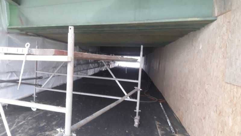 Gerüstturm unter dem Überbau einer Brücke, Arbeitsebene direkt unter dem Bauwerk